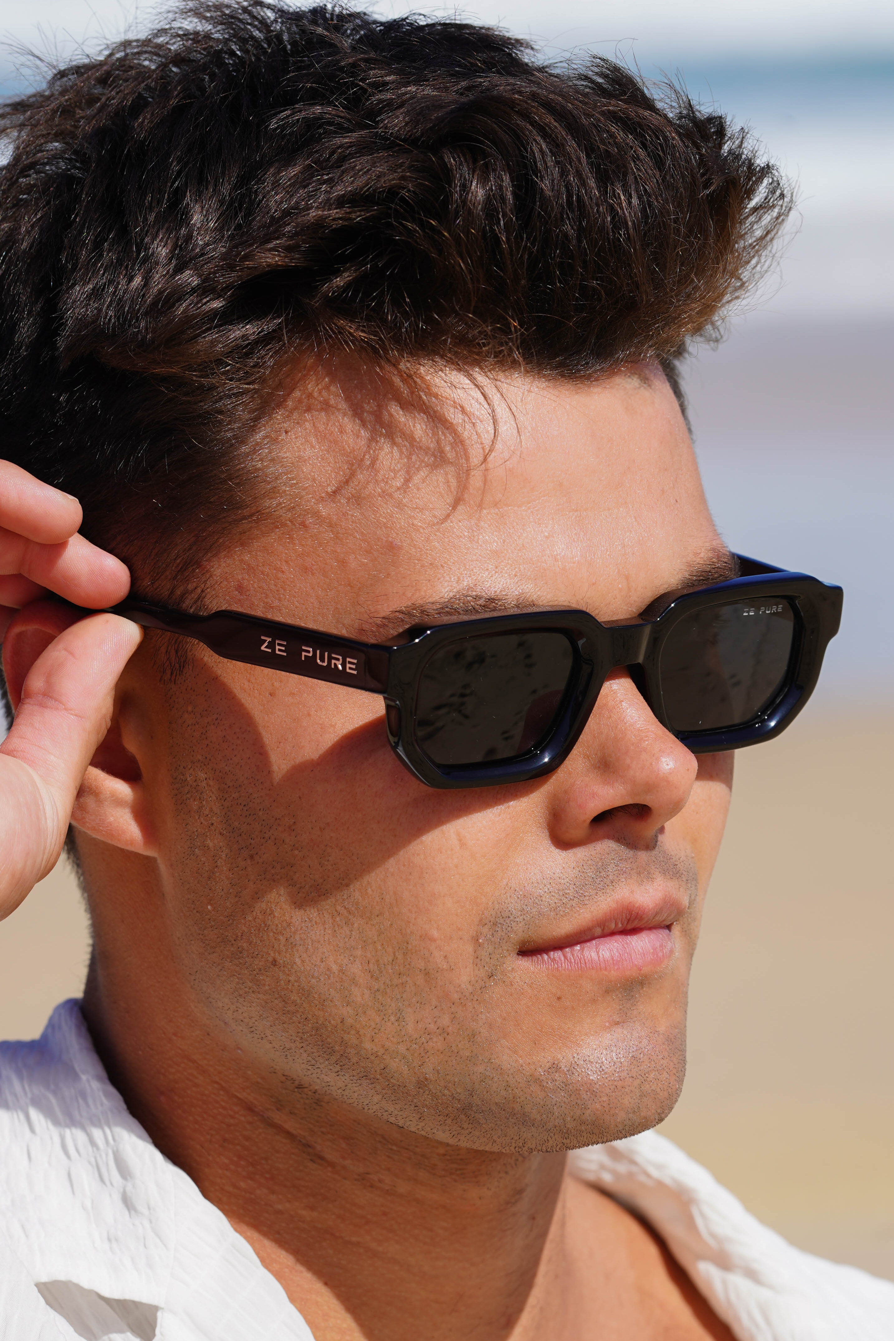 Man wearing sunglasses with a blurred beach background