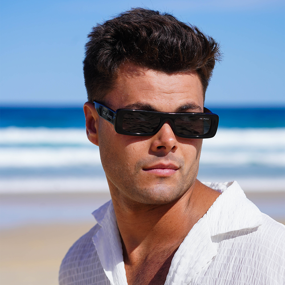 Man wearing sunglasses with a beach and blue sky in the background