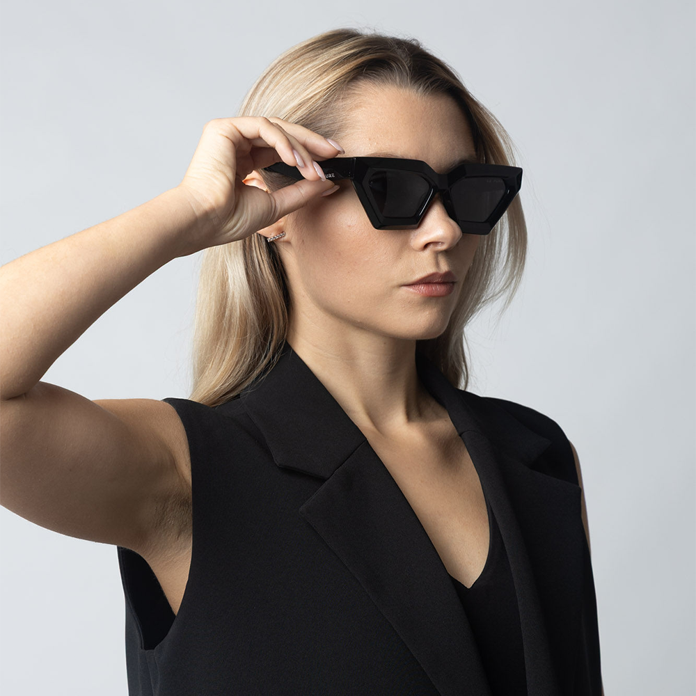 Woman wearing black sunglasses against a light gray background