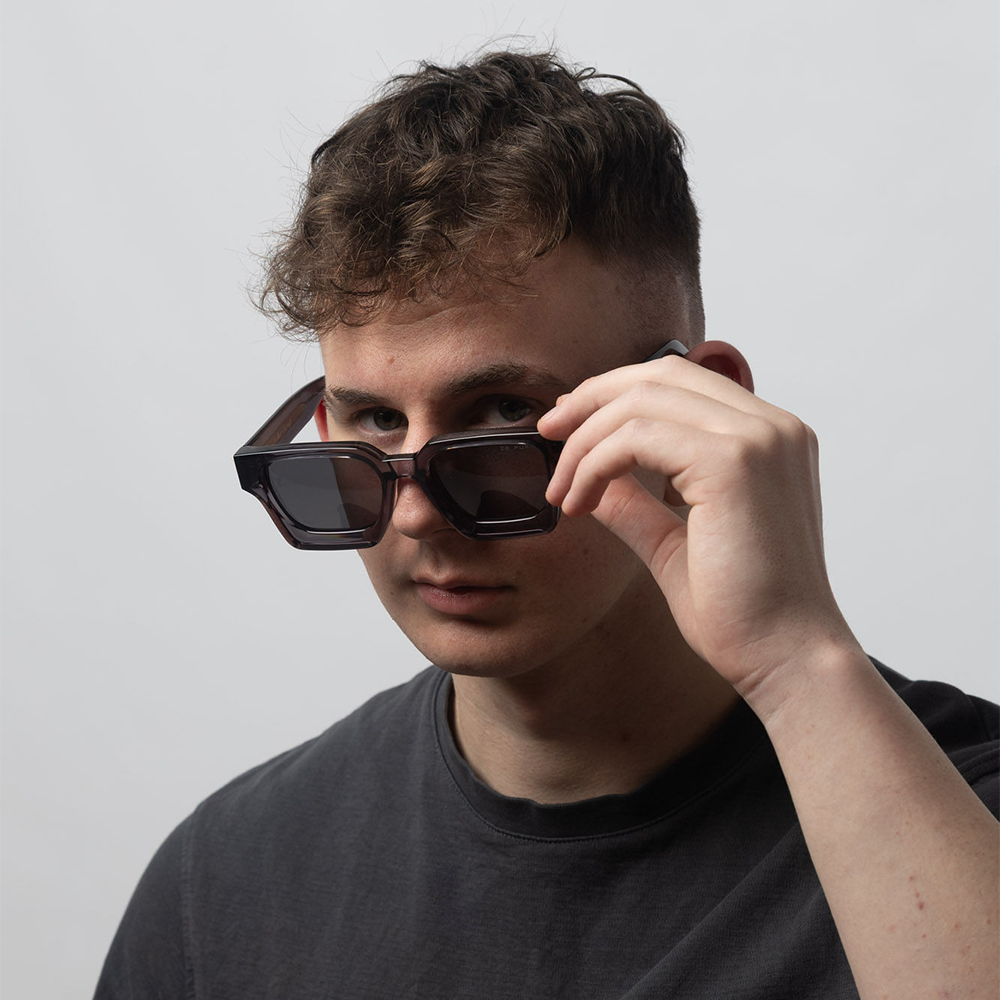 Person wearing dark sunglasses with a plain background